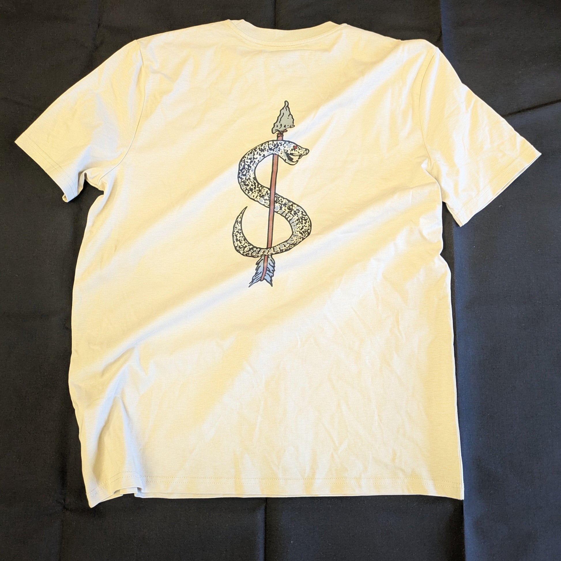 Light yellow t-shirt with a graphic design on the back against a black background
